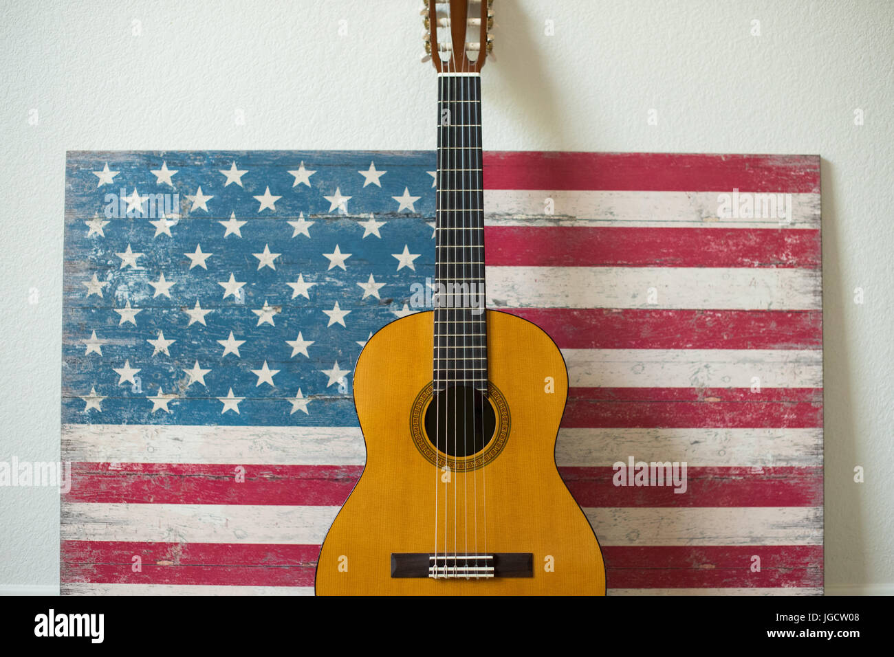Chitarra appoggiata contro una bandiera americana dipinto su legno Foto Stock