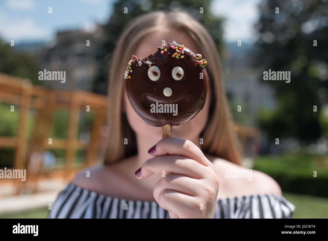 Donna che mantiene un buon viso di gelati nella parte anteriore del suo viso Foto Stock