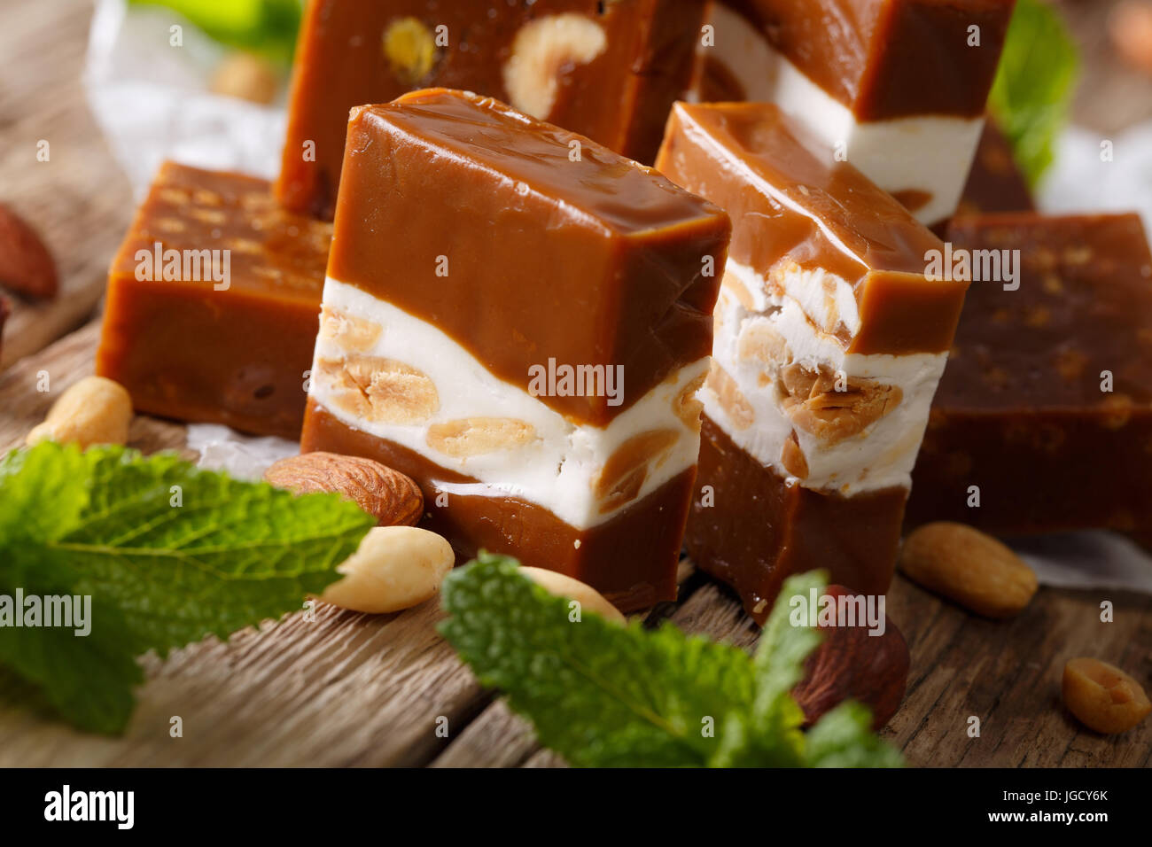Toffee con torrone e mandorle, menta fresca macro sul tavolo orizzontale. Foto Stock