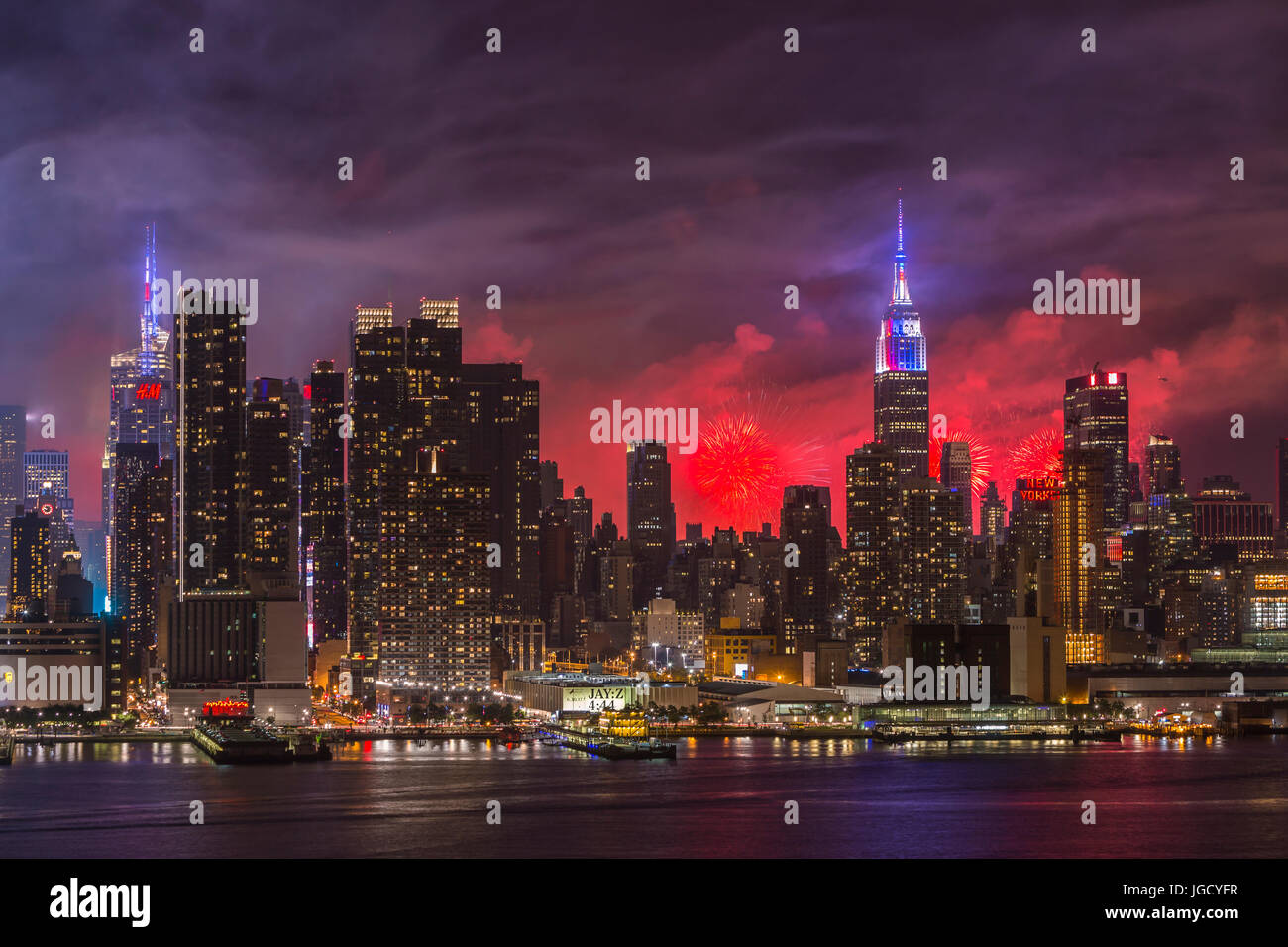 L annuale Macy's quarta di luglio mostra fuochi d'artificio illumina il cielo dietro la skyline di Manhattan a New York City come viste attraverso il fiume Hudson. Foto Stock