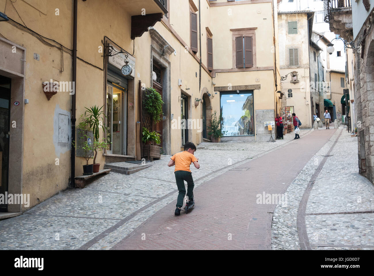 Un ragazzo su un kick scooter in una piccola città in Italia Foto Stock