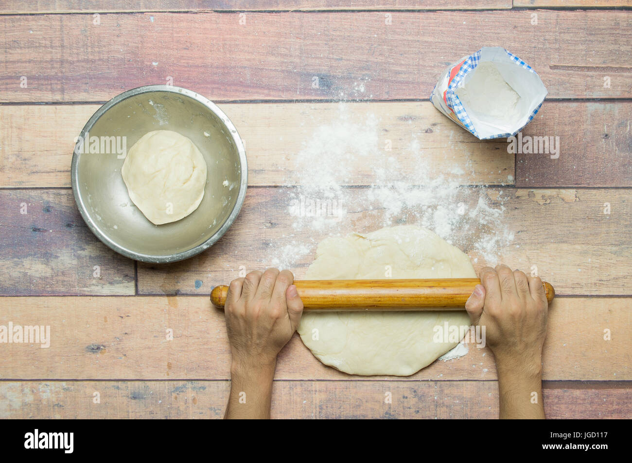 Pasta di stiro con il mattarello sul tavolo di legno per la cottura Foto Stock