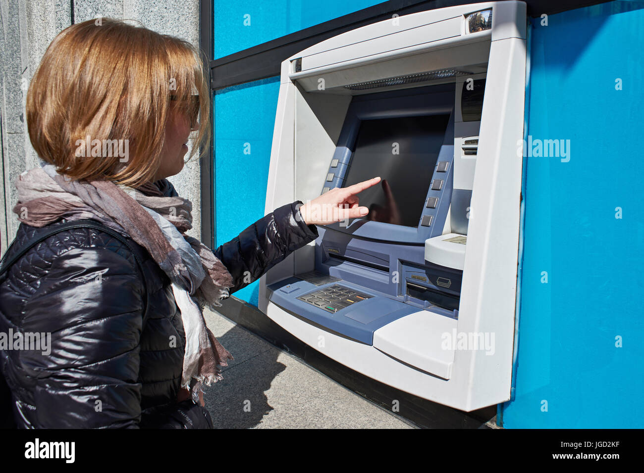 La donna utilizza il touchscreen su ATM Foto Stock