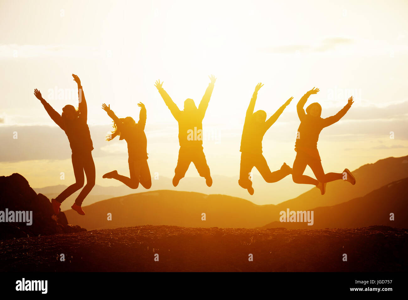 Happy amici jumping montagne al tramonto Foto Stock