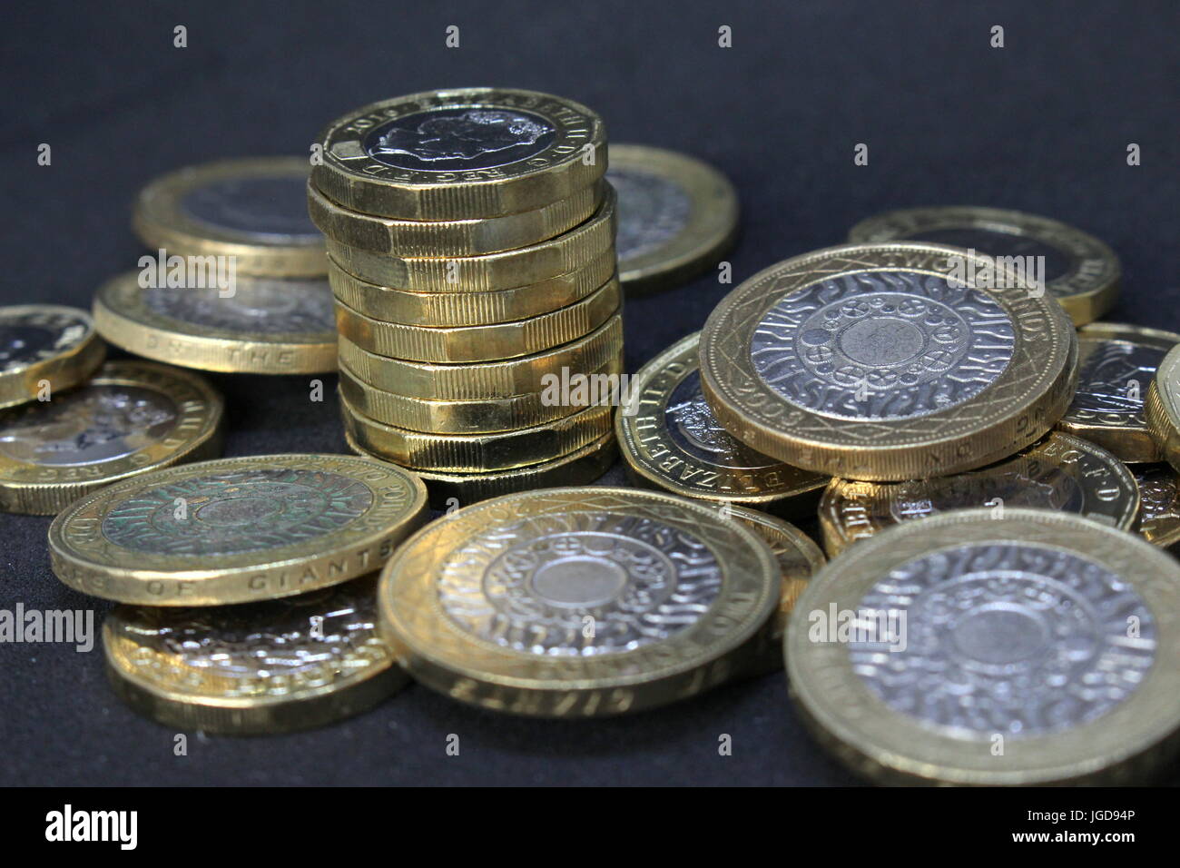Un mucchio di sterlina inglese monete - nuova lira monete e due-pound monete contro uno sfondo scuro Foto Stock