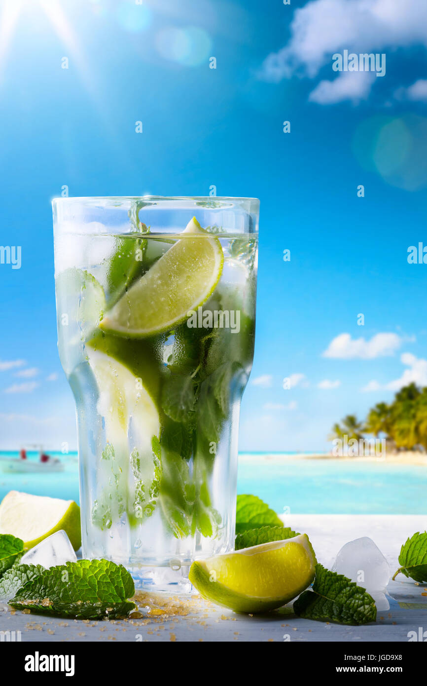 Tropico vacanza estiva; drink esotici sulla sfocatura spiaggia tropicale sfondo Foto Stock