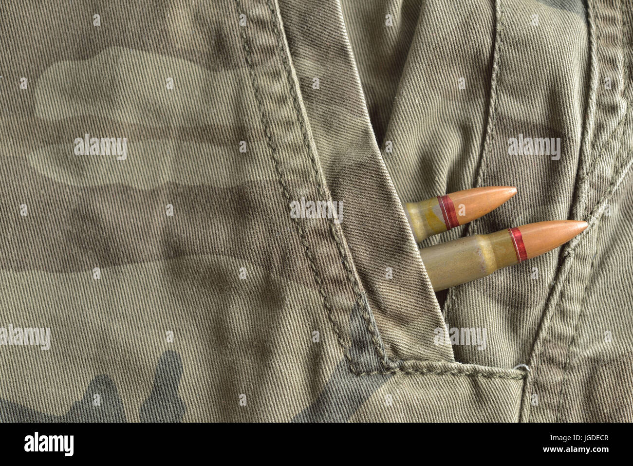 Due proiettili di fucile nascosto in militari tasca camo pantaloni. munizioni militari Foto Stock
