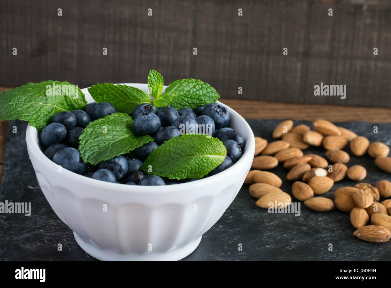 Sani frutti - mirtilli e il giallo dei limoni in una ciotola bianco - crudo, deliziosi e nutrienti, alimenti funzionali Foto Stock