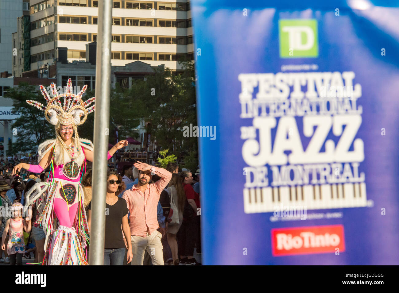 Montreal, 3 Luglio 2017: artista su stilt in costume colorato a piedi dietro un Jazz Festival Poster Foto Stock