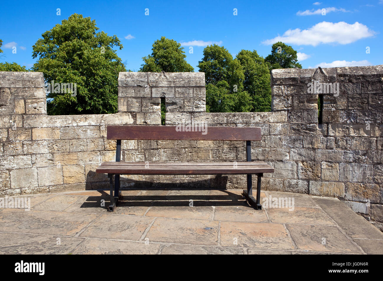 Una panca in legno sulla pietra medievali mura dell'antica e storica città di York nel periodo estivo. Foto Stock