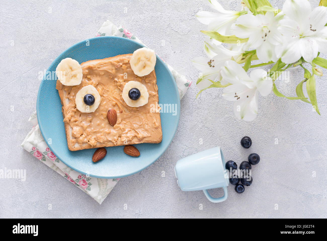 La colazione / snack / scuola il pranzo per i bambini: burro di arachidi toast con banana, mirtillo e mandorle a forma di gufo divertenti sulla piastra di blu. Vista superiore Foto Stock