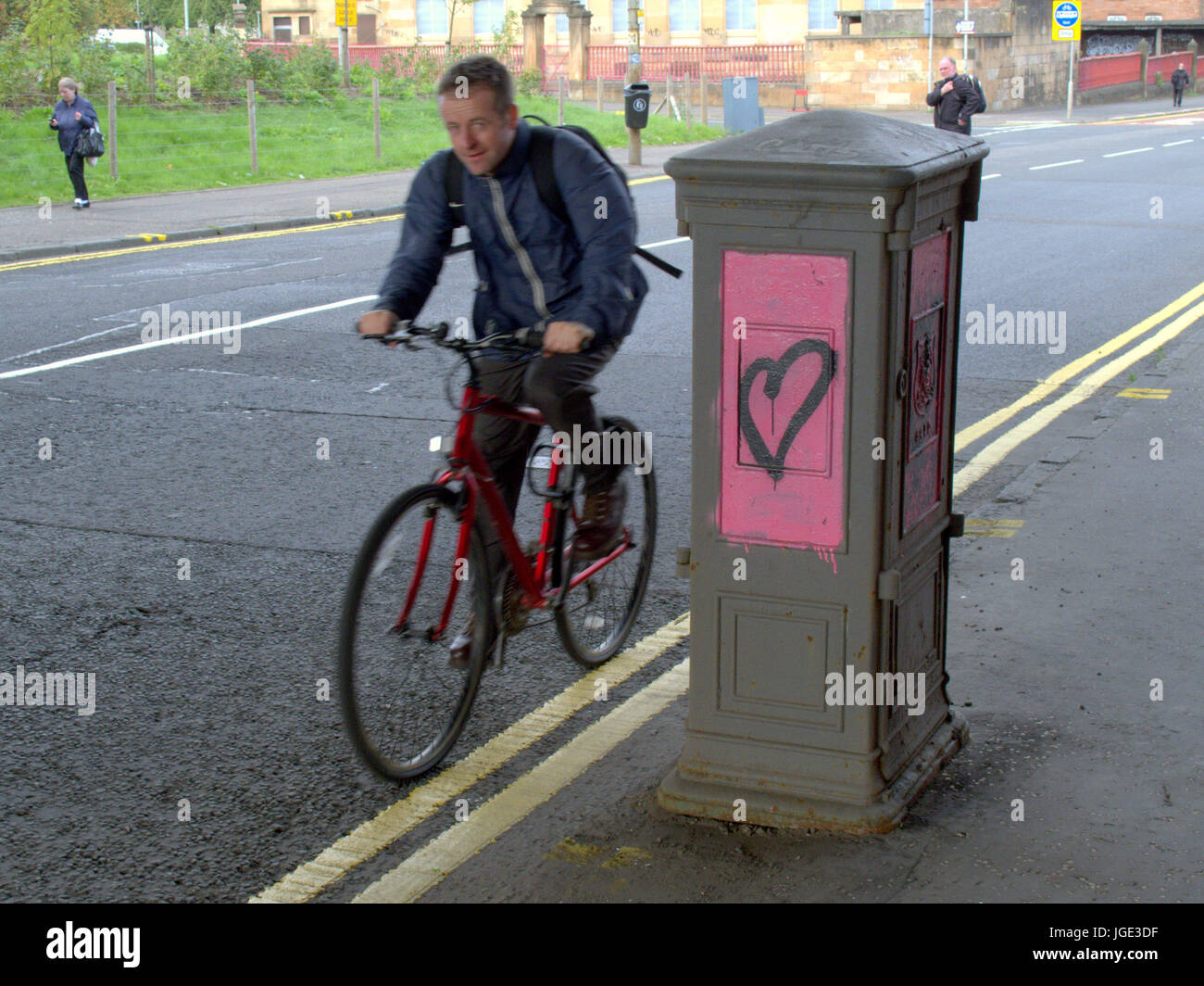 Glasgow street ciclista passando graffiti cuore rosa Foto Stock