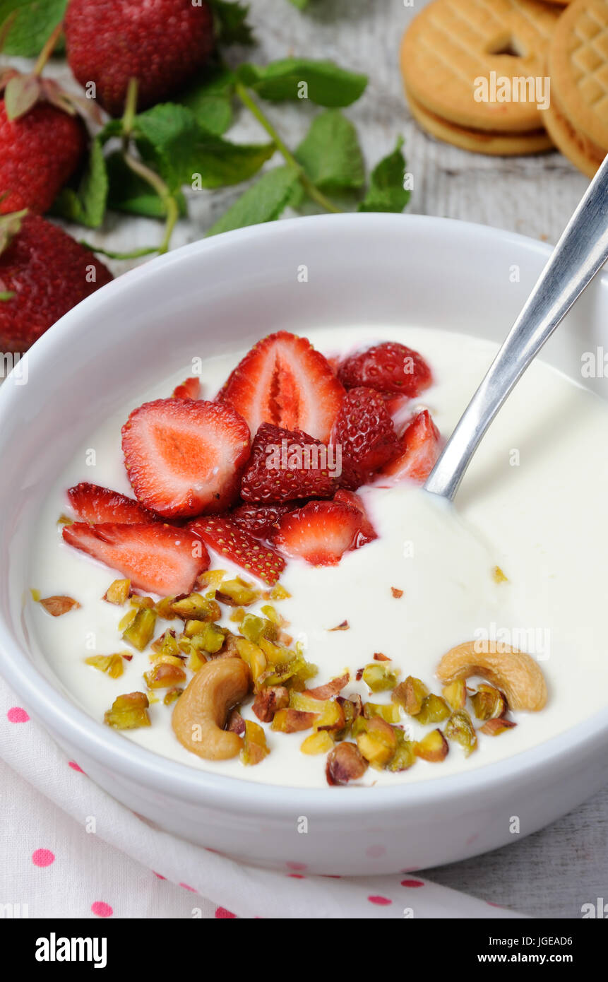 Refrigerate latticello zuppa da yogurt greco con le fragole e i pistacchi anacardi. Servire con biscotti croccanti. Colpo verticale. Foto Stock