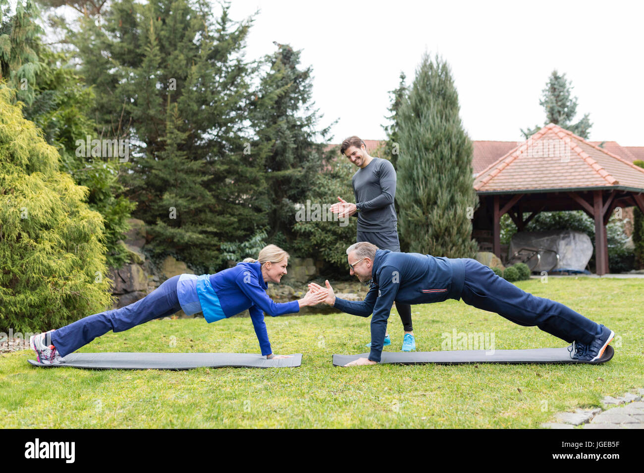 Coppia si esercita con un personal trainer in giardino Foto Stock