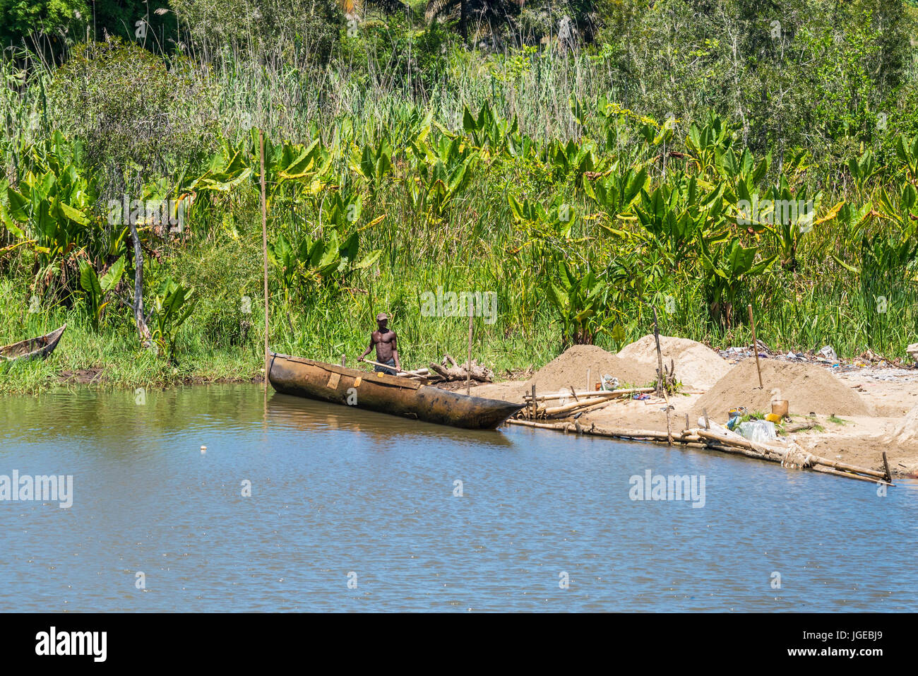 Ivoloina, Madagascar - Dicembre 22, 2015: campagna malgascio l uomo dal villaggio di sabbia di scarico da tradizionale a mano piroga barche di legno vicino al Foto Stock