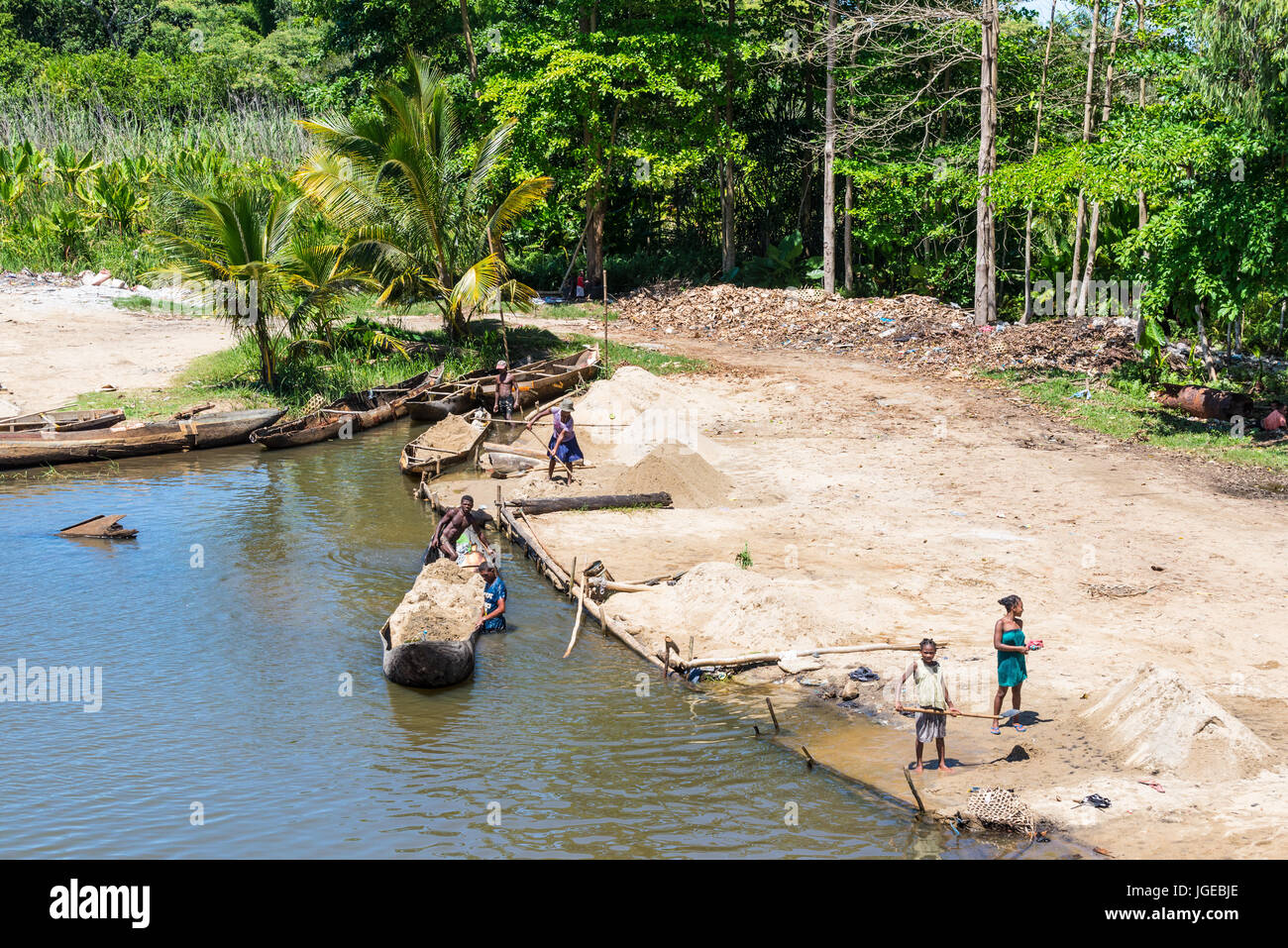 Ivoloina, Madagascar - Dicembre 22, 2015: campagna malgascio persone dal villaggio di sabbia di scarico da tradizionale a mano piroga barche di legno vicino Foto Stock
