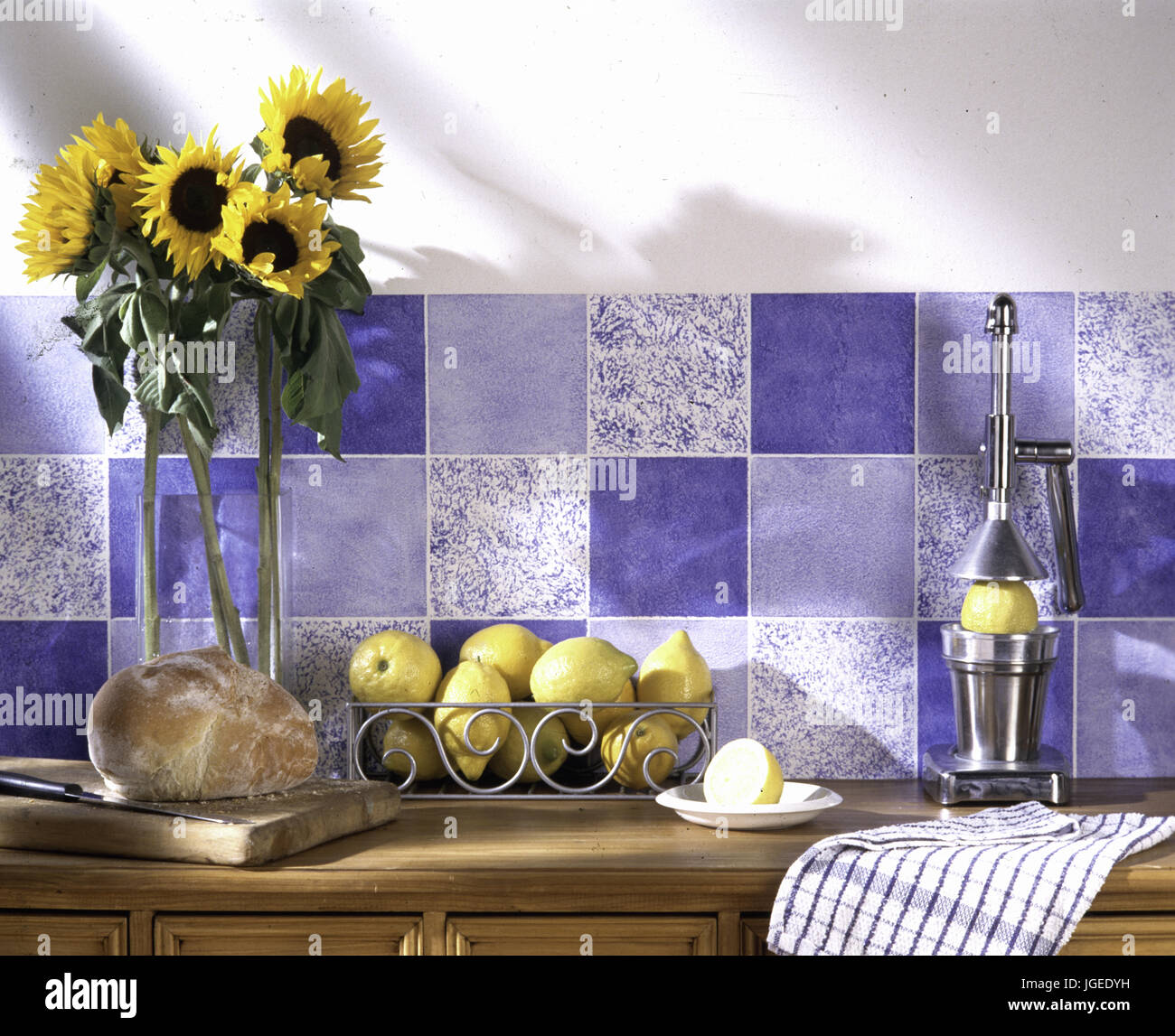 Chrome limone premere e Vaso con girasoli blu contro la parete piastrellata Foto Stock