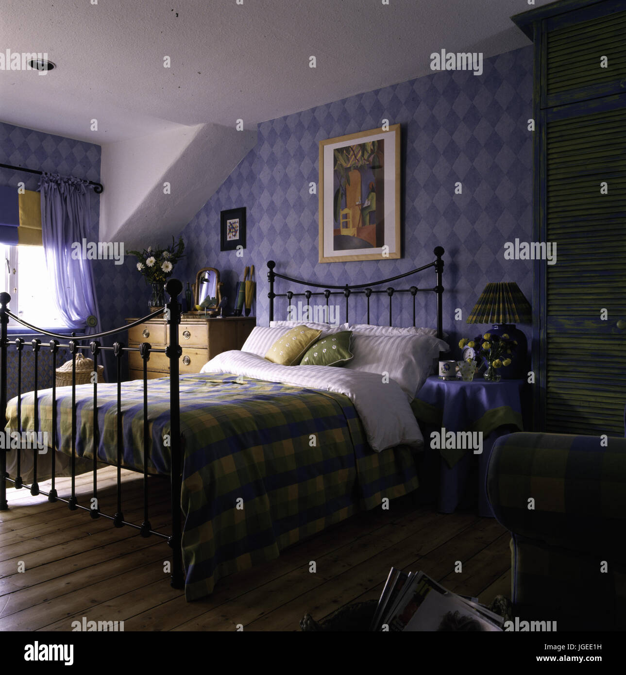 Vintage letto di ferro battuto in una tradizionale camera mansardata con sfondo blu Foto Stock