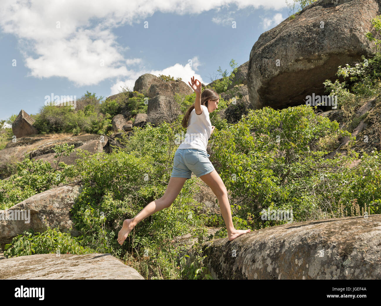 Giovani caucasici fitness bella donna correre a piedi nudi a rocce di montagna Foto Stock