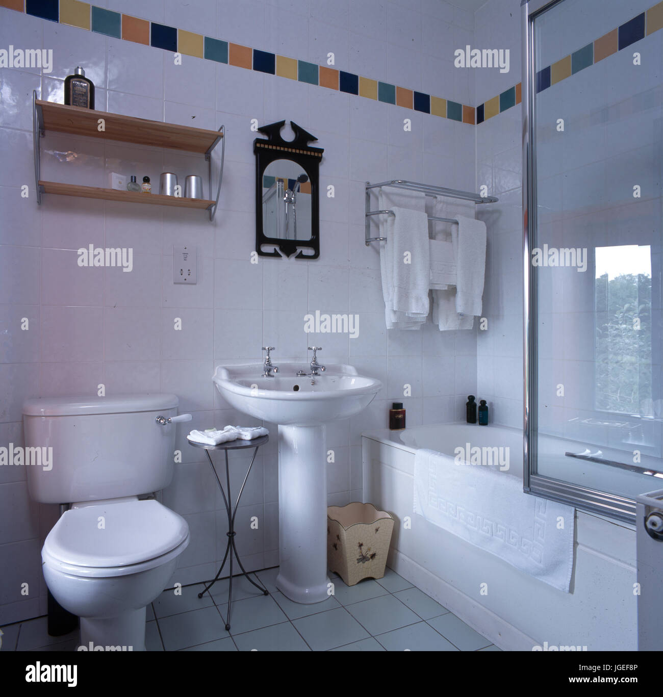 Bagno in piastrelle bianche con banda di piastrelle colorate all'altezza del soffitto Foto Stock