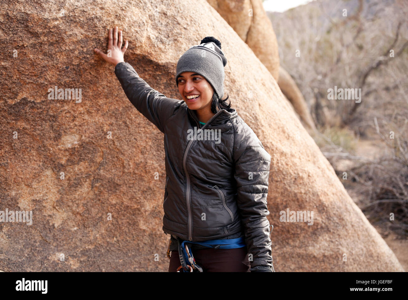 Sud giovane donna asiatica arrampicata su roccia nel deserto vestito per basse temperature Foto Stock