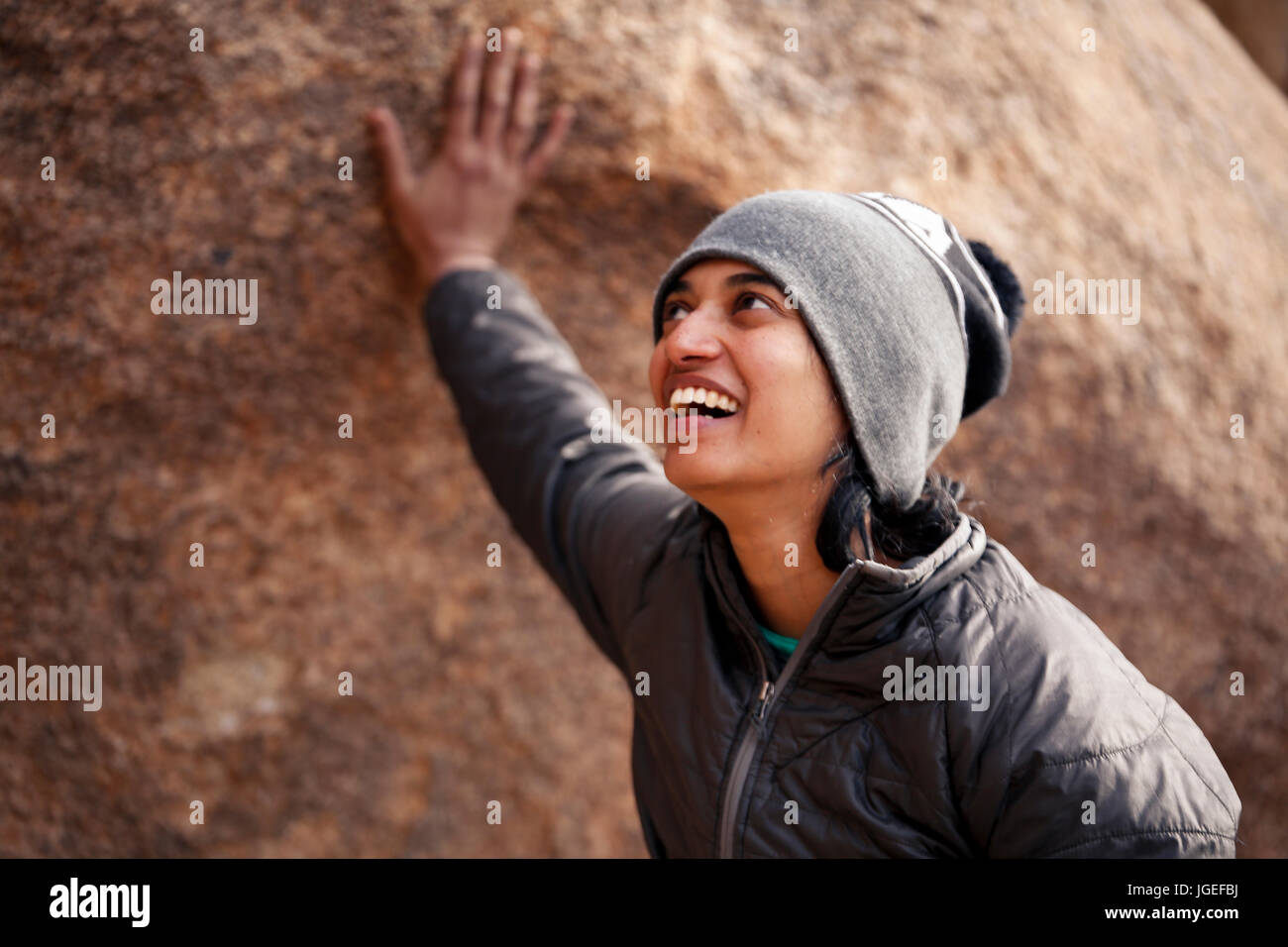 Sud giovane donna asiatica arrampicata su roccia nel deserto vestito per basse temperature Foto Stock
