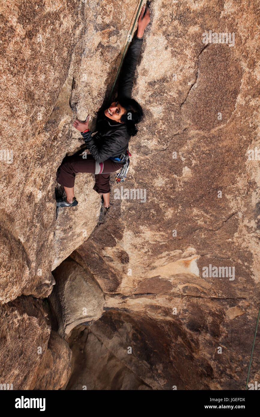 Sud giovane donna asiatica rock si arrampica nel deserto su un molto difficile parete Foto Stock