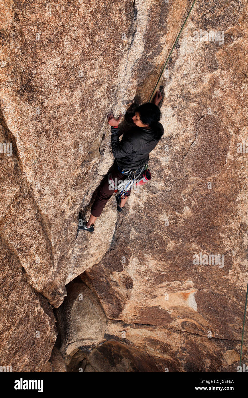 Sud giovane donna asiatica rock si arrampica nel deserto su un molto difficile parete Foto Stock