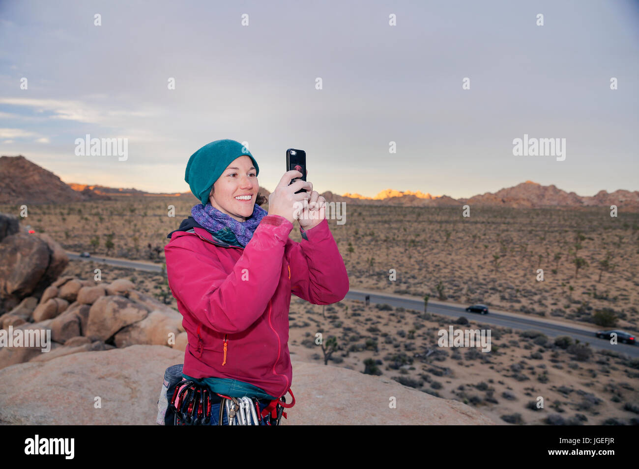 Giovane donna caucasica arrampicata su roccia nel deserto vestito per basse temperature Foto Stock