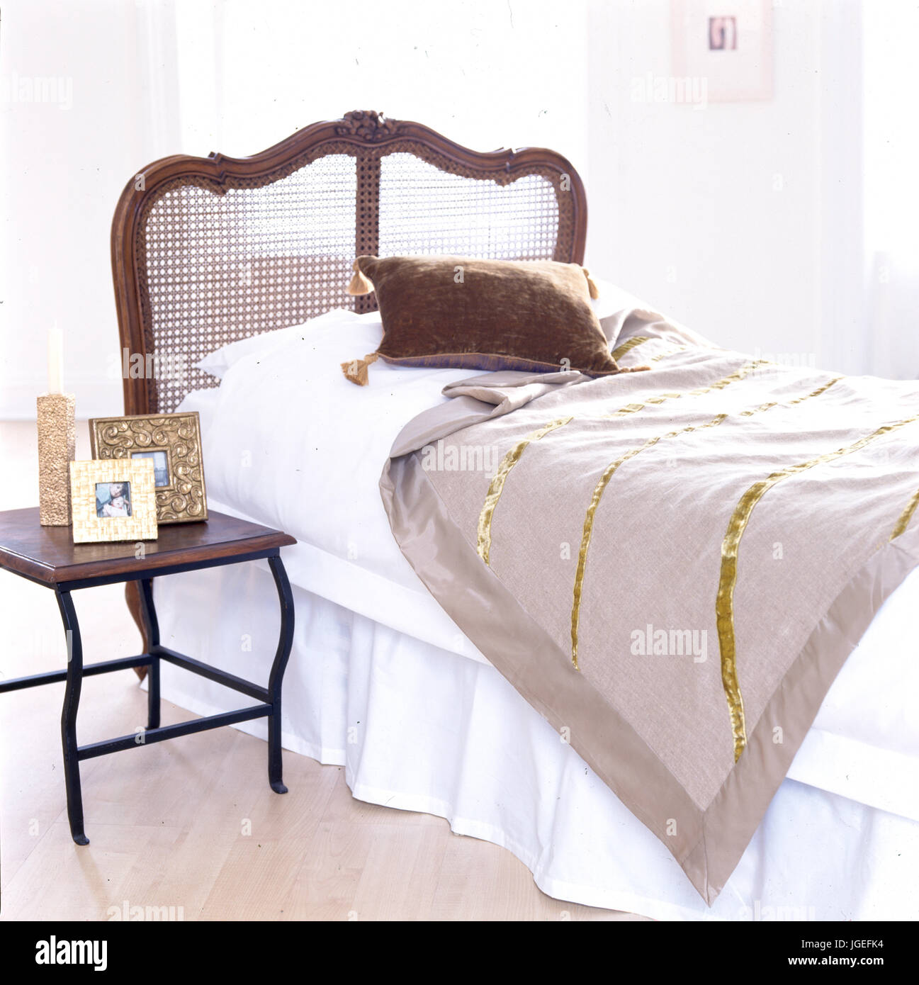 Canne intrecciate sulla testiera letto con biancheria bianca e orlata di lino beige gettare Foto Stock