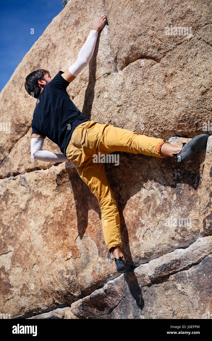 Giovane uomo caucasico rock si arrampica nel deserto senza corde o attrezzature di sicurezza Foto Stock