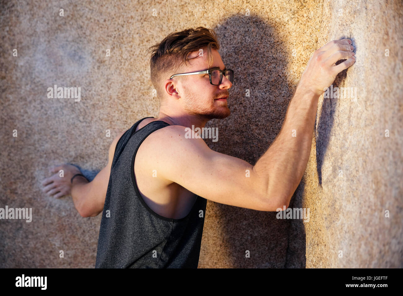 Montare giovane uomo caucasico con gli occhiali rock si arrampica nel deserto Foto Stock