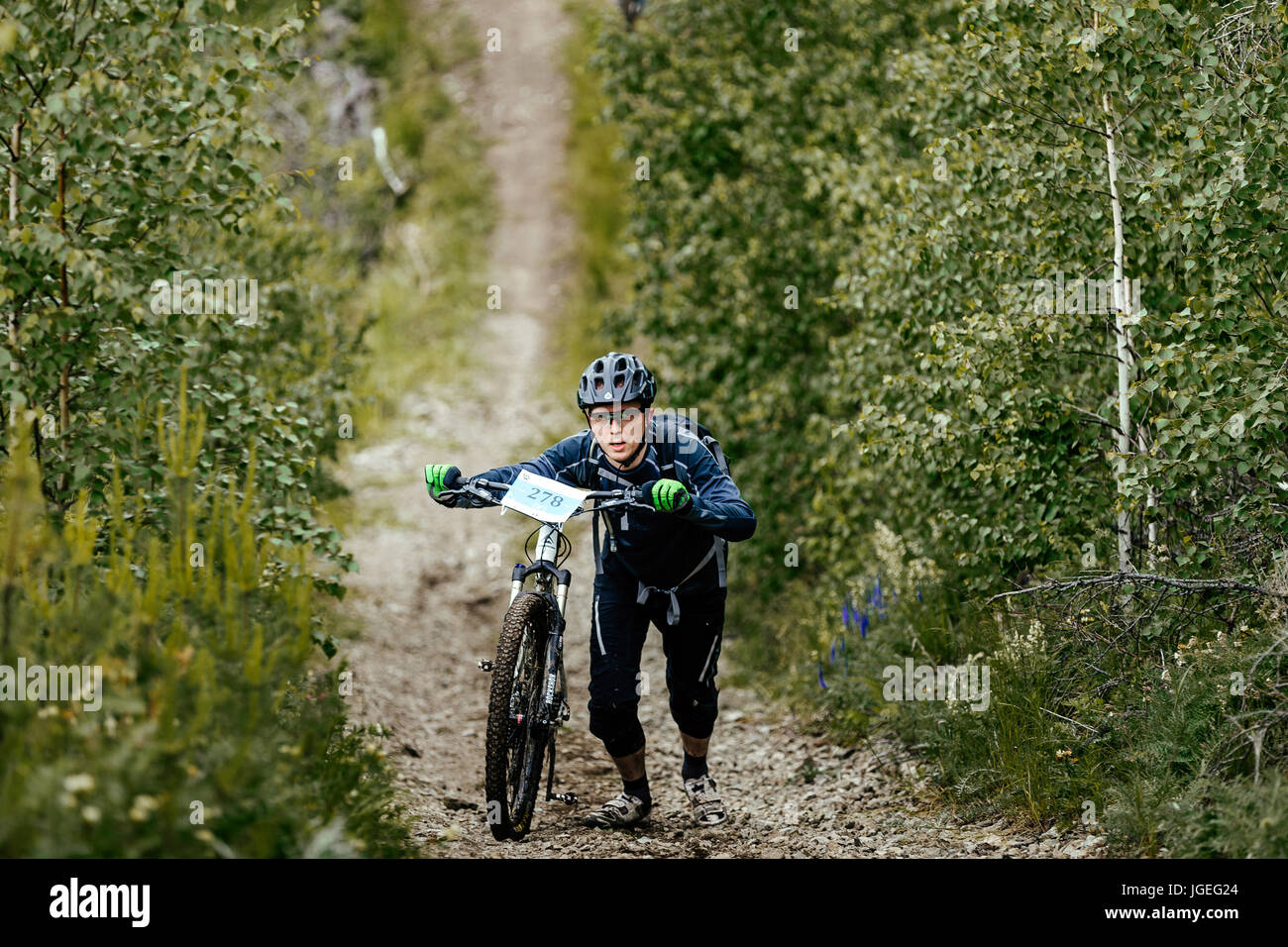 L'uomo ciclista con bicicletta sportiva di camminata in salita durante i campionati regionali in mountain bike Foto Stock