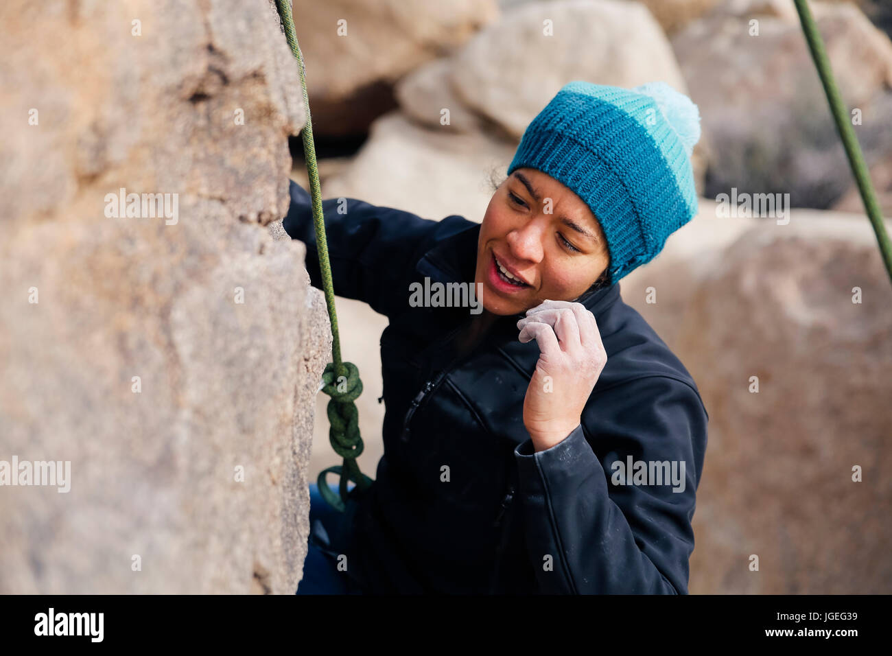 Giovani razza mista donna vestita per basse temperature salite di roccia nel deserto Foto Stock