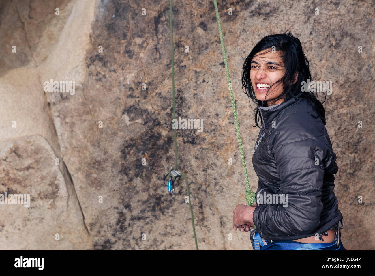 Sud giovane donna asiatica arrampicata su roccia nel deserto vestito per basse temperature Foto Stock