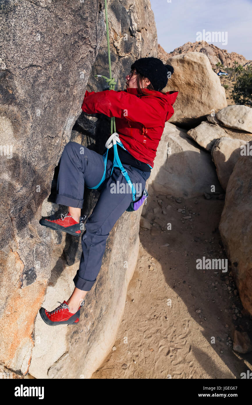 Giovane donna caucasica con gli occhiali vestito per basse temperature salite di roccia nel deserto Foto Stock