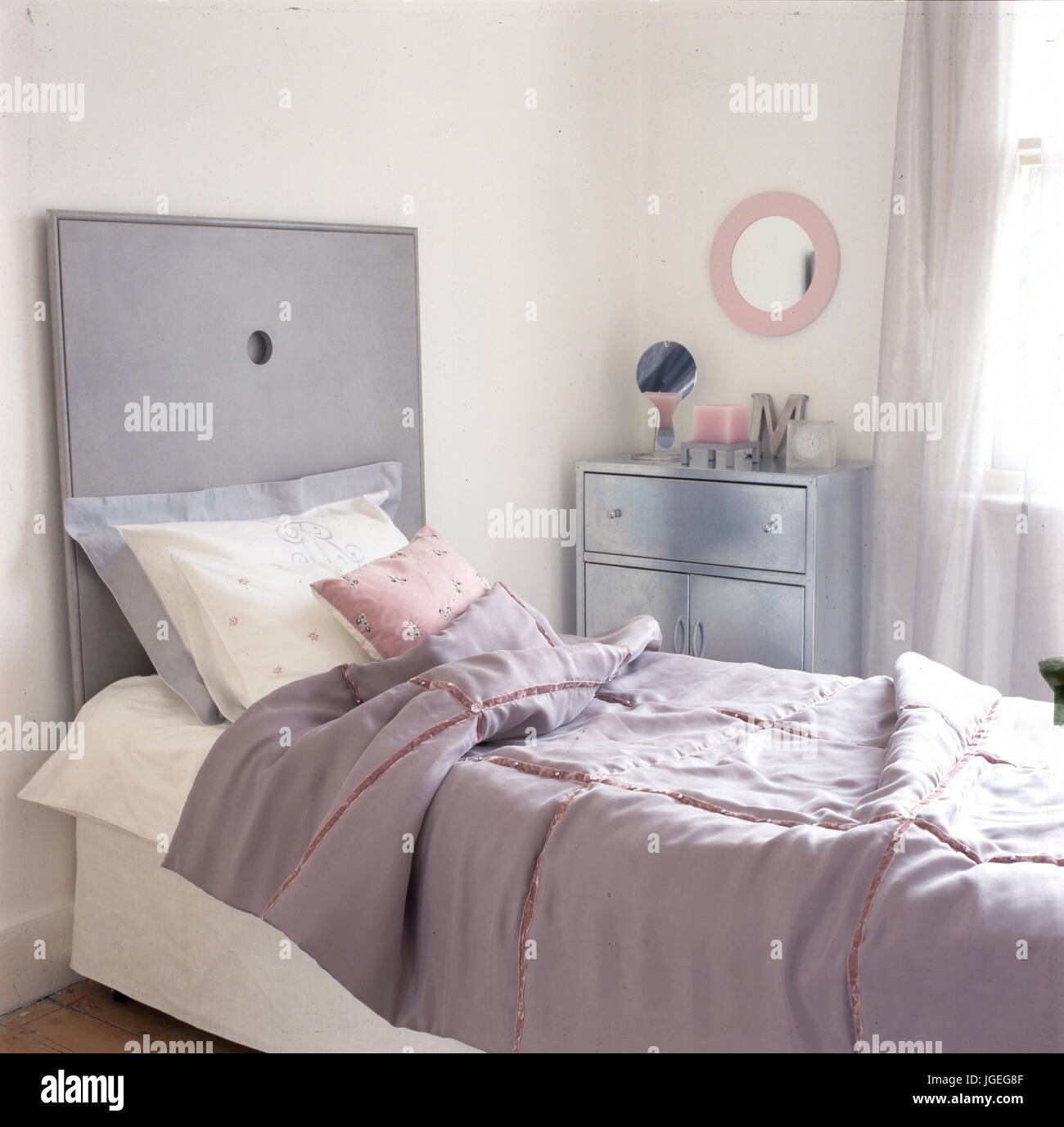Letto singolo nella camera femminile con rosa e grigio schema colori Foto Stock