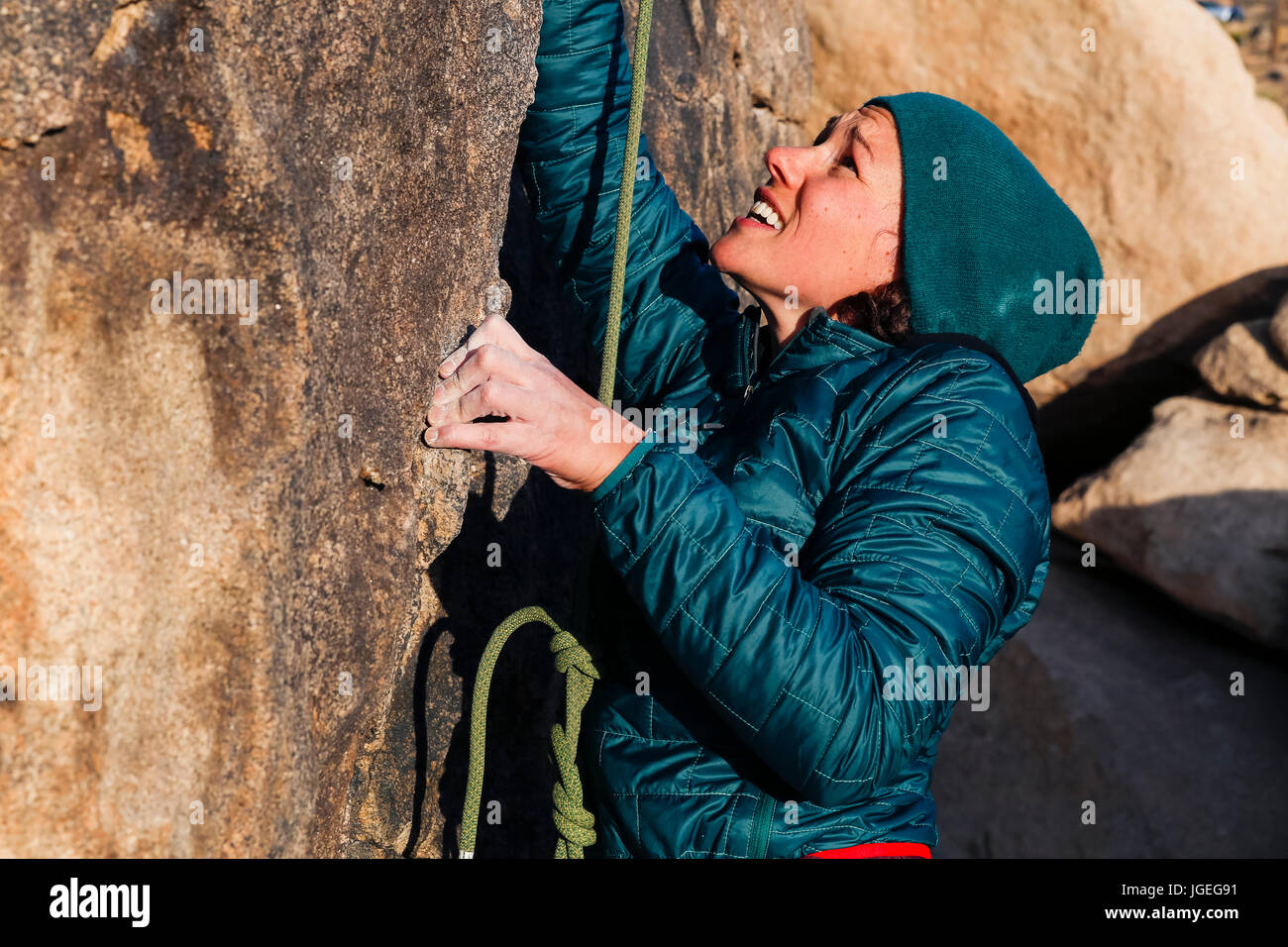 Giovane donna caucasica vestito per basse temperature arrampicata su roccia nel deserto Foto Stock