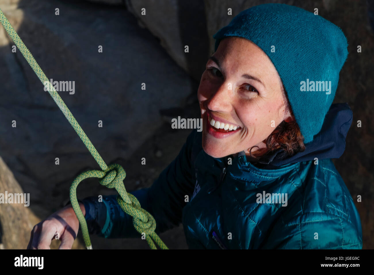 Giovane donna caucasica vestito per basse temperature arrampicata su roccia nel deserto Foto Stock