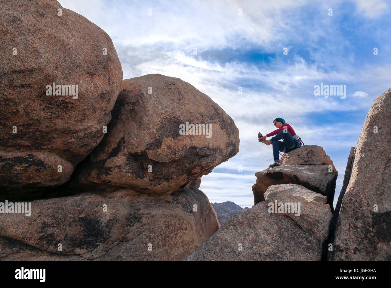 Giovani razza mista donna rock si arrampica nel deserto con attrezzatura tecnica mentre vestita per basse temperature Foto Stock