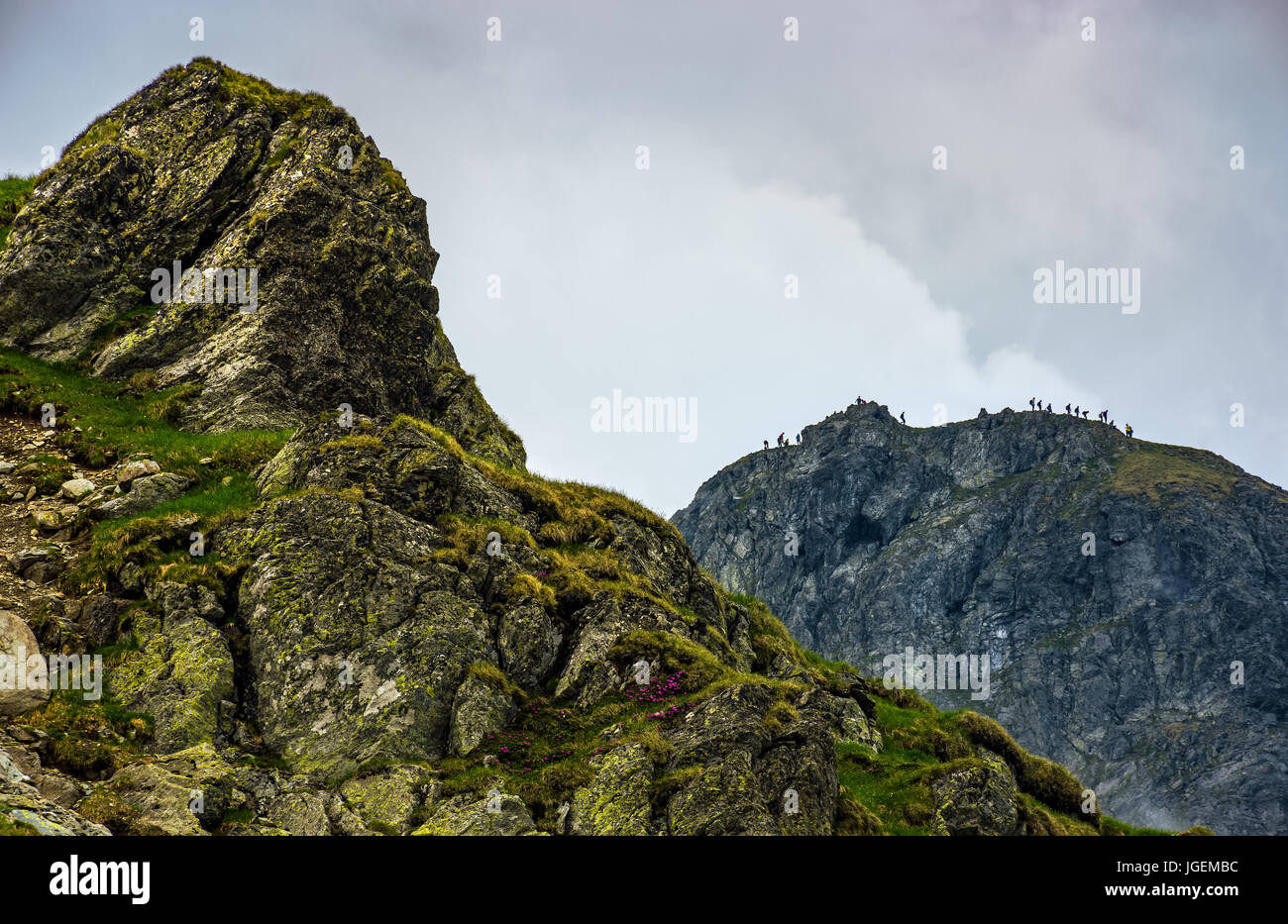 Enorme pietra sul bordo di una collina. felici turisti raggiungono la loro destinazione in montagna Foto Stock