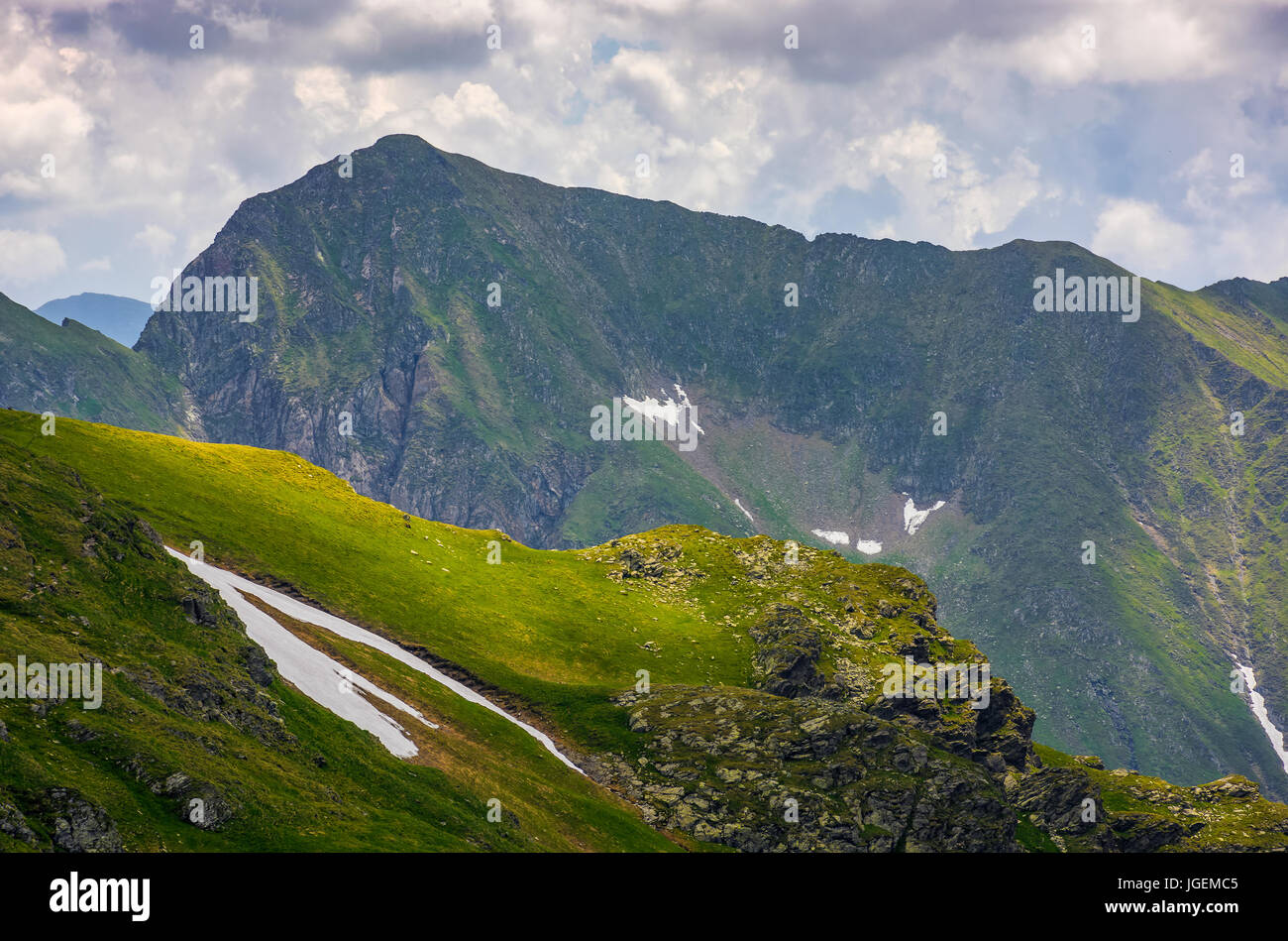 Bordo roccioso sul pendio erboso con neve. majestic dei Carpazi paesaggio estivo in Romania le montagne Foto Stock