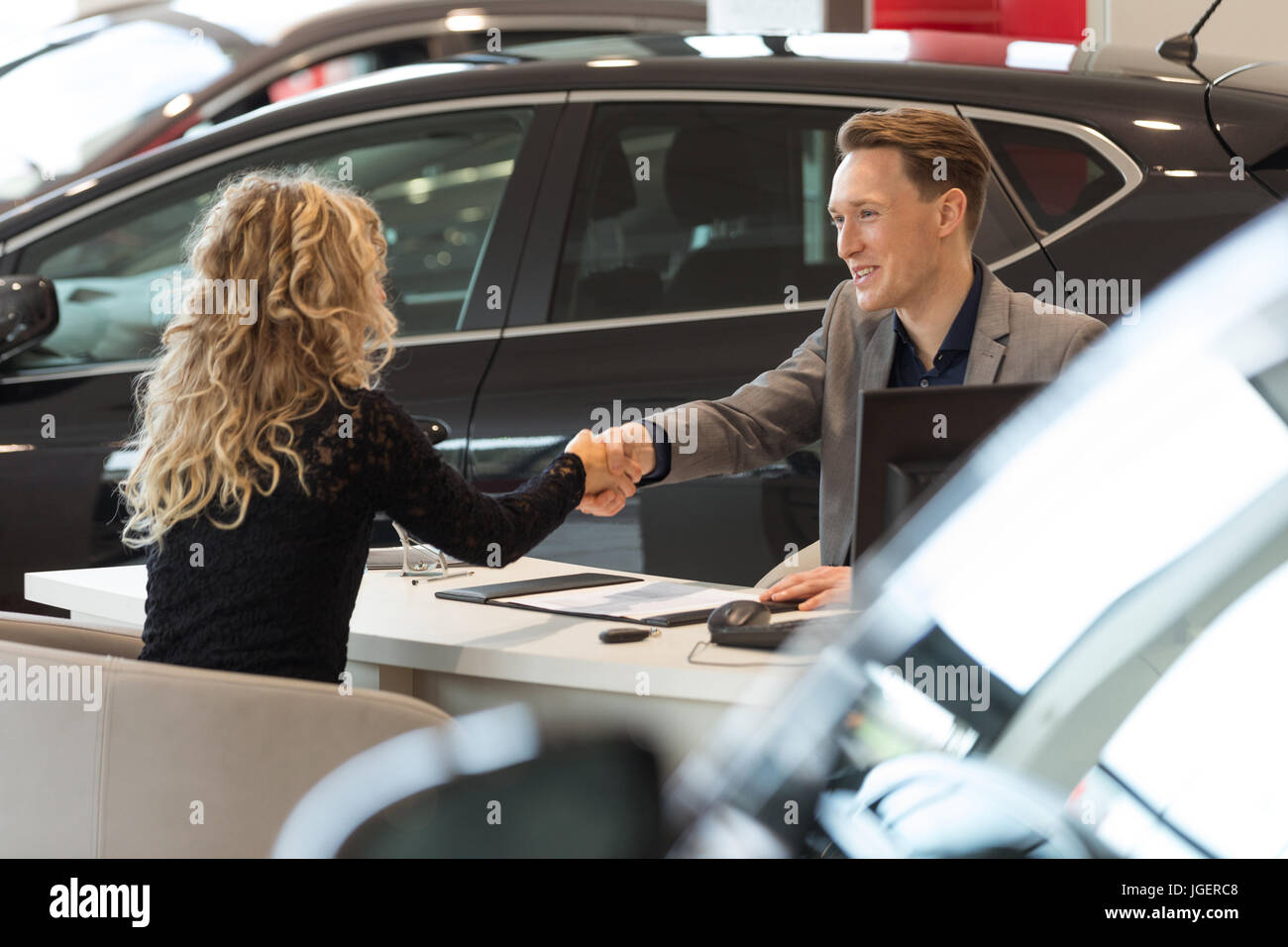 Sorridente venditore facendo handshake con il cliente femmina Foto Stock