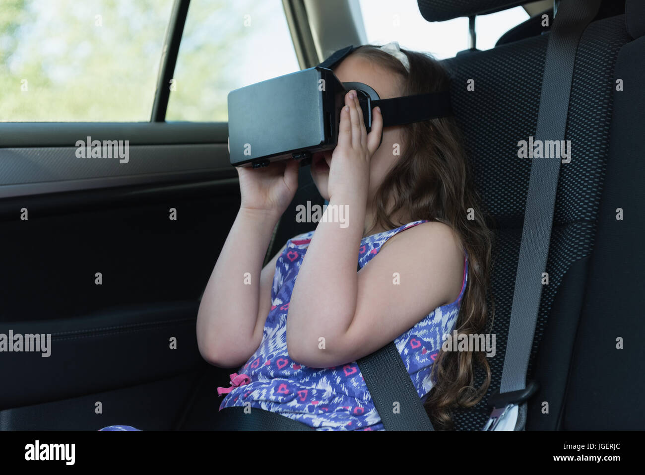 Bambina utilizzando la realtà virtuale auricolare in auto Foto Stock