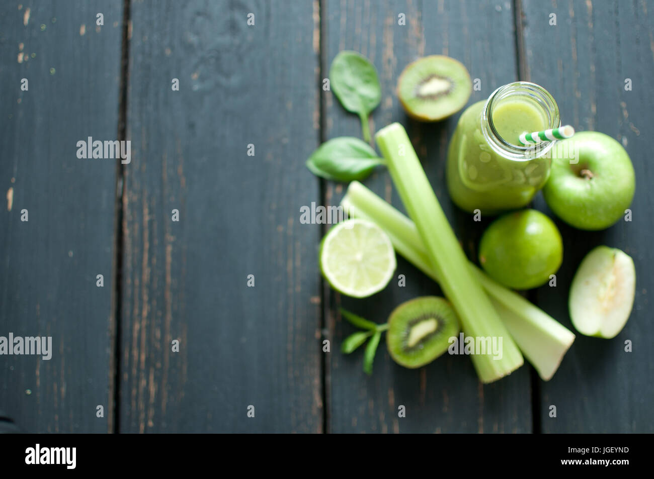 Frullato verde bottiglia con ingredienti sul tavolo di legno Foto Stock