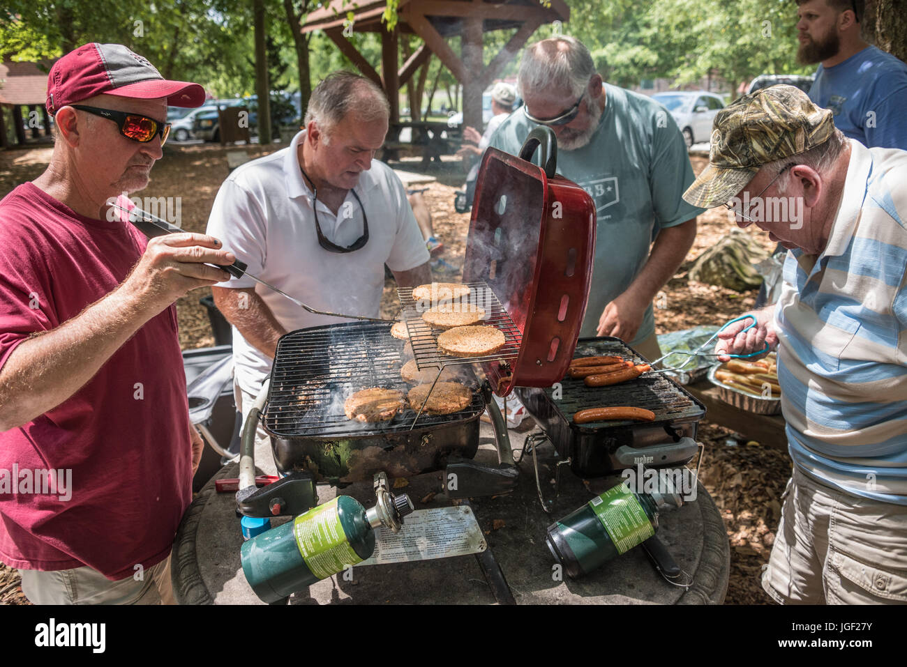 Gli uomini la grigliatura hamburger e hot dogs per un estate famiglia raccolta lungo il fiume Chattahoochee in Helen, Georgia. (USA) Foto Stock