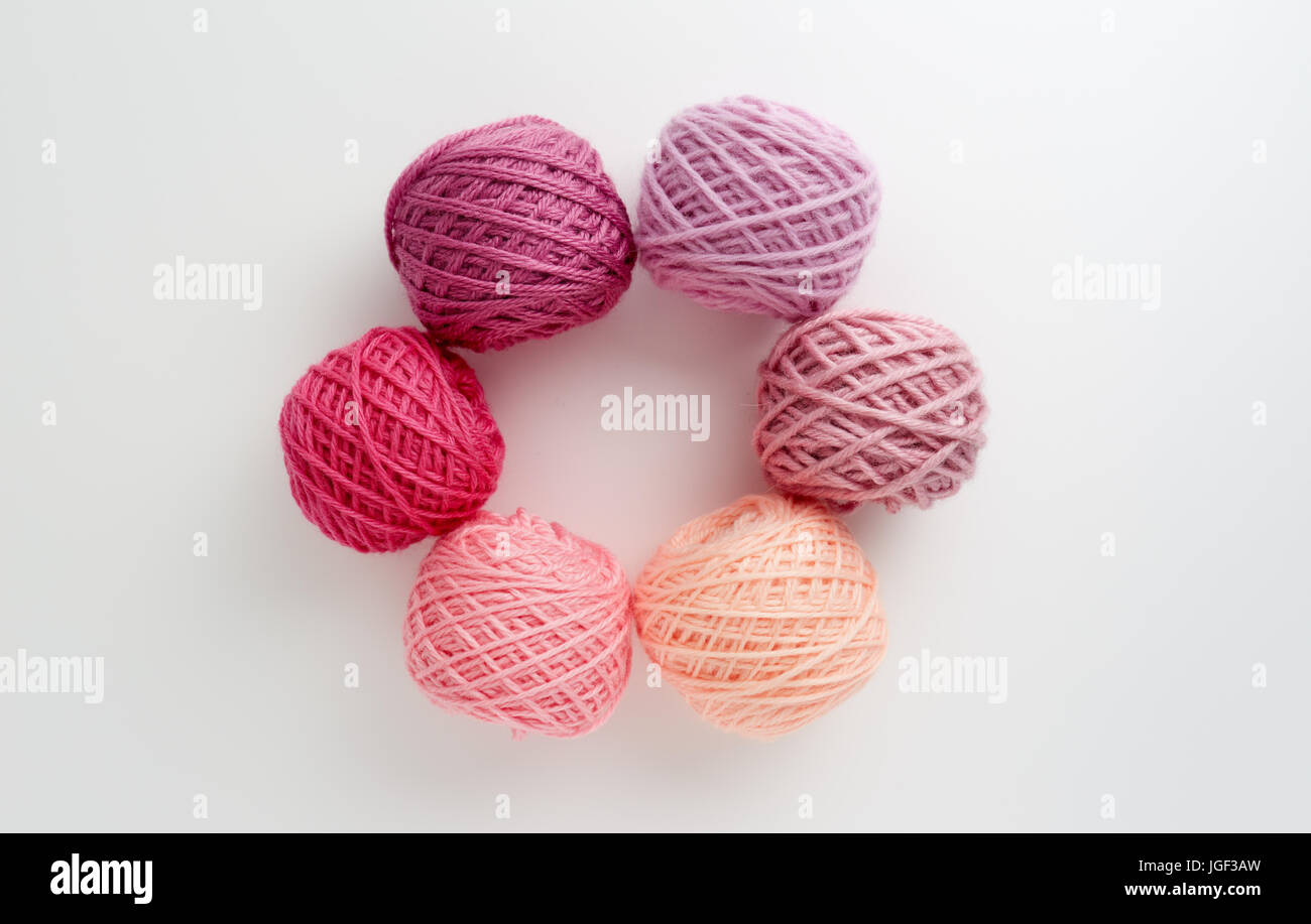 Filati per maglieria di palline in tono di colore rosa. Filato colorato su uno sfondo bianco. Matasse di filo di lana per maglieria. Foto Stock