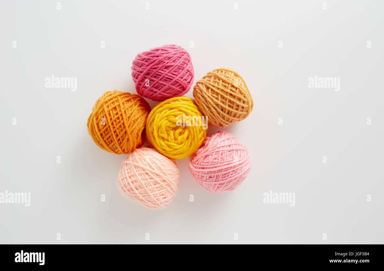 Filati per maglieria a sfere in rosa e il tono di colore giallo. Filato colorato su uno sfondo bianco. Matasse di filo di lana per maglieria. Foto Stock