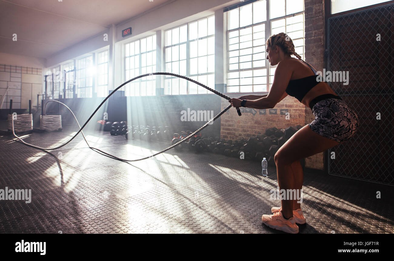 Donna di sollevamento pesi pesanti in palestra per allenare la muscolatura. Atleta esercizio utilizzando una barra di peso. Foto Stock