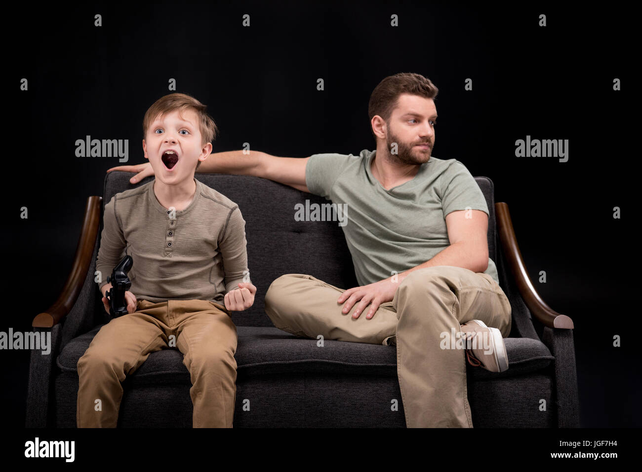 Sconvolto padre seduto sul divano vicino al piccolo figlio di giocare con il joystick, problemi familiari concetto Foto Stock